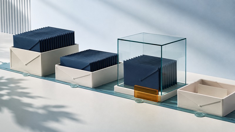 Navy envelope records sit in ivory trays along a teal track, with one group protected inside a glass case marked in amber.