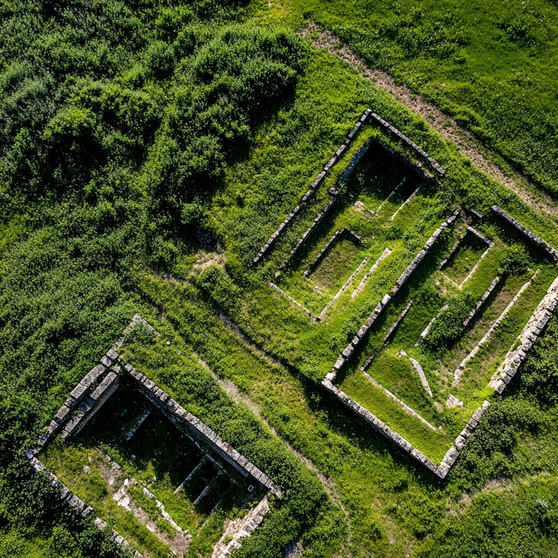 Aerial view of a cultural heritage site with two large rectangular structures and smaller ones connected by pathways.